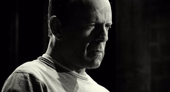 Movie still from “Sin City” (2005), directed by Frank Miller – Black and white photograph of a man with a shaved head; Close Up shot, Low angle