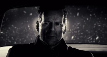 Movie still from “Sin City” (2005), directed by Frank Miller – Black and white photograph of a man in a car; Close Up shot, Low angle