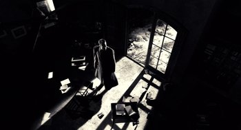 Movie still from “Sin City” (2005), directed by Frank Miller – A man standing in a room with a chair and a window; Wide shot, Low angle