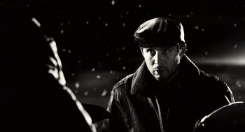 Movie still from “Sin City” (2005), directed by Frank Miller – A black and white photo of a man wearing a hat; Close Up shot, Over the shoulder angle