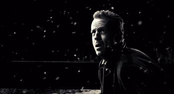 Movie still from “Sin City” (2005), directed by Frank Miller – A black and white photo of a man in the snow; Close Up shot, Low angle