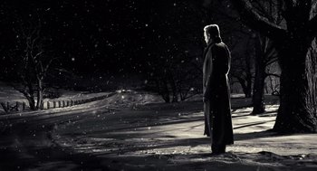 Movie still from “Sin City” (2005), directed by Frank Miller – A man standing in the middle of a snow covered field at night; Wide shot, Low angle