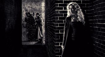 Movie still from “Sin City” (2005), directed by Frank Miller – A woman standing in front of a brick wall; Wide shot, Over the shoulder angle
