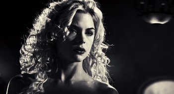 Movie still from “Sin City” (2005), directed by Frank Miller – A woman with long blonde curly hair posing for a picture; Close Up shot, Low angle