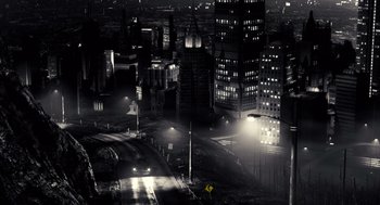 Movie still from “Sin City” (2005), directed by Frank Miller – An aerial view of a city at night with street lights; Extreme Wide shot, High angle