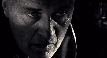Movie still from “Sin City” (2005), directed by Frank Miller – An old man with green eyes looking at the camera; Extreme Close Up shot, Low angle