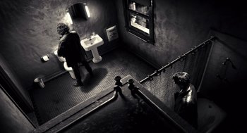 Movie still from “Sin City” (2005), directed by Frank Miller – A man sitting on the stairs of a bathroom next to a sink; Extreme Wide shot, High angle