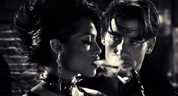 Movie still from “Sin City” (2005), directed by Frank Miller – A man and a woman are smoking a cigarette together; Close Up shot, Low angle