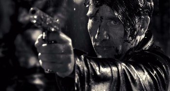 Movie still from “Sin City” (2005), directed by Frank Miller – Black and white photograph of a man holding a gun; Close Up shot, Over the shoulder angle
