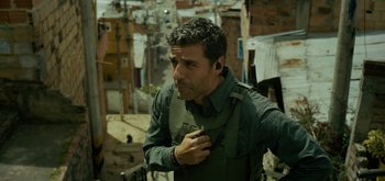 Movie still from “Triple Frontier” (2019), directed by J.C. Chandor – A man in a green shirt is smoking a cigarette; Medium shot, Over the shoulder angle