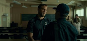 Movie still from “Triple Frontier” (2019), directed by J.C. Chandor – A man standing next to another man in a room; Medium shot, Over the shoulder angle