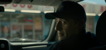Movie still from “Triple Frontier” (2019), directed by J.C. Chandor – A person in a car wearing a hat; Close Up shot, Over the shoulder angle
