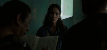 Movie still from “Triple Frontier” (2019), directed by J.C. Chandor – A woman is reading a book in the dark; Close Up shot, Over the shoulder angle