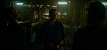 Movie still from “Triple Frontier” (2019), directed by J.C. Chandor – A man standing in the dark in front of a bar; Medium shot, Over the shoulder angle