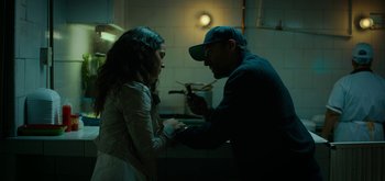 Movie still from “Triple Frontier” (2019), directed by J.C. Chandor – A man and a woman are holding hands in a kitchen; Medium shot, Low angle