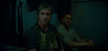 Movie still from “Triple Frontier” (2019), directed by J.C. Chandor – A man in a military uniform and a man in a green hat; Medium shot, Over the shoulder angle