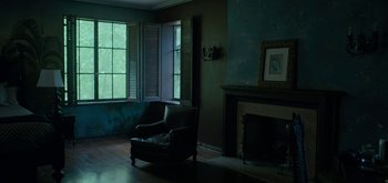 Movie still from “Triple Frontier” (2019), directed by J.C. Chandor – A living room with a chair and a fire place; Wide shot, High angle