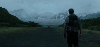 Movie still from “Triple Frontier” (2019), directed by J.C. Chandor – A man standing in front of an airplane on a runway; Extreme Wide shot, Over the shoulder angle