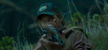 Movie still from “Triple Frontier” (2019), directed by J.C. Chandor – A man with a hat on and a gun in his hand; Close Up shot, Over the shoulder angle