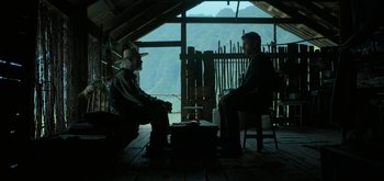 Movie still from “Triple Frontier” (2019), directed by J.C. Chandor – Two men sitting in chairs in front of a window; Wide shot, Over the shoulder angle