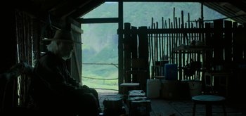 Movie still from “Triple Frontier” (2019), directed by J.C. Chandor – A person sitting in a room with a view of a mountain; Wide shot, Over the shoulder angle