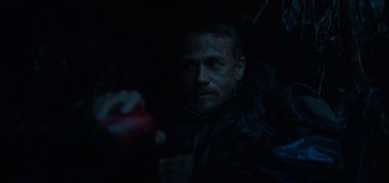 Movie still from “Triple Frontier” (2019), directed by J.C. Chandor – A man in a black jacket holding a red apple; Close Up shot, High angle