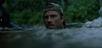 Movie still from “Triple Frontier” (2019), directed by J.C. Chandor – A person wearing a hat in the water; Close Up shot, Over the shoulder angle