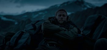 Movie still from “Triple Frontier” (2019), directed by J.C. Chandor – A man with a backpack sitting on a hill; Medium shot, High angle