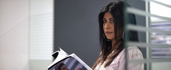 Movie still from “Trippin' with the Kandasamys” (2021), directed by Jayan Moodley – A woman is holding a magazine in her hands; Close Up shot, High angle