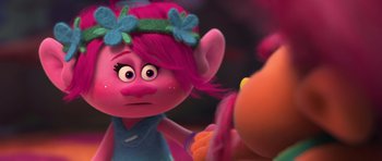 Movie still from “Trolls” (2016), directed by Mike Mitchell – A pink haired troll looking at another troll in the background; Close Up shot, Over the shoulder angle
