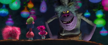 Movie still from “Trolls” (2016), directed by Mike Mitchell – A purple monster is standing in front of a troll; Medium shot, Over the shoulder angle