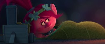 Movie still from “Trolls” (2016), directed by Mike Mitchell – A pink haired girl with a flower headband is looking at a ball of yarn; Medium shot, High angle