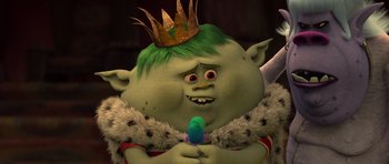 Movie still from “Trolls” (2016), directed by Mike Mitchell – A green troll with a crown on his head and holding a blue object; Close Up shot, High angle