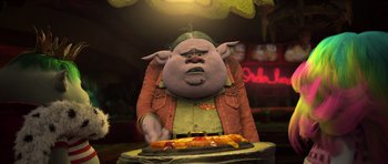 Movie still from “Trolls” (2016), directed by Mike Mitchell – An animated character sitting in front of a table with a pizza on it; Medium shot, High angle