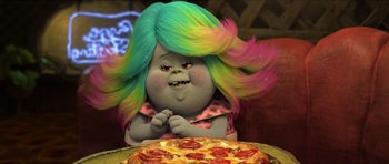 Movie still from “Trolls” (2016), directed by Mike Mitchell – A person with a troll doll hair sitting in front of a pizza; Close Up shot, Over the shoulder angle