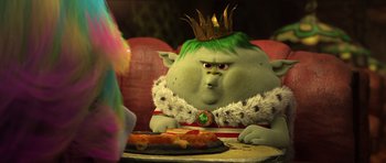 Movie still from “Trolls” (2016), directed by Mike Mitchell – A troll with a crown sitting in front of a plate of food; Medium shot, Over the shoulder angle