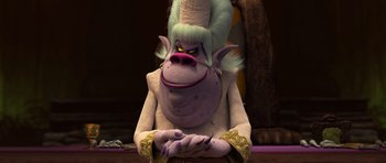 Movie still from “Trolls” (2016), directed by Mike Mitchell – A monkey with a white wig sitting on top of a wooden table; Medium shot, Over the shoulder angle