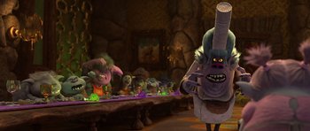Movie still from “Trolls” (2016), directed by Mike Mitchell – A group of people sitting at a table with food on it; Medium shot, Over the shoulder angle