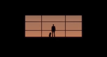 Movie still from “Tully” (2018), directed by Jason Reitman – A man standing in front of a window with a suitcase; Extreme Wide shot, Low angle