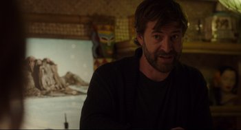 Movie still from “Tully” (2018), directed by Jason Reitman – A bearded man sitting in front of a painting; Medium shot, Over the shoulder angle