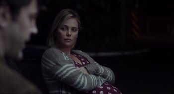 Movie still from “Tully” (2018), directed by Jason Reitman – A woman sitting with her arms crossed in the dark; Medium shot, Over the shoulder angle