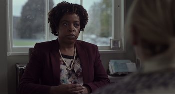 Movie still from “Tully” (2018), directed by Jason Reitman – A woman in a red jacket is sitting in front of a window; Close Up shot, Over the shoulder angle
