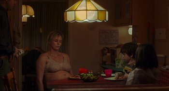Movie still from “Tully” (2018), directed by Jason Reitman – A woman sitting at a table with a plate of food in front of her; Medium shot, Over the shoulder angle