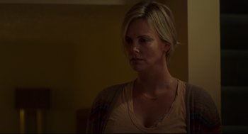 Movie still from “Tully” (2018), directed by Jason Reitman – A woman is looking at the camera while standing in a dimly - lit room; Close Up shot, Over the shoulder angle