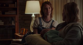 Movie still from “Tully” (2018), directed by Jason Reitman – A woman sitting on a couch holding a baby; Medium shot, Over the shoulder angle
