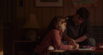 Movie still from “Tully” (2018), directed by Jason Reitman – Two people sitting at a table and one is writing on a piece of paper; Medium shot, Over the shoulder angle