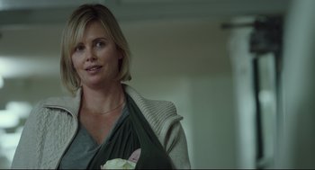 Movie still from “Tully” (2018), directed by Jason Reitman – A woman in a gray shirt holding a white flower; Close Up shot, Over the shoulder angle