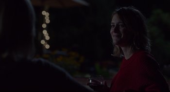 Movie still from “Tully” (2018), directed by Jason Reitman – A woman holding a wine glass in her right hand; Medium shot, Over the shoulder angle