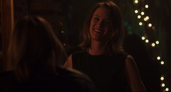 Movie still from “Tully” (2018), directed by Jason Reitman – A woman smiling at the camera in a dark room; Close Up shot, Over the shoulder angle