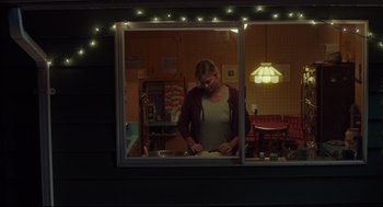 Movie still from “Tully” (2018), directed by Jason Reitman – A woman standing in front of a store window at night; Wide shot, Over the shoulder angle